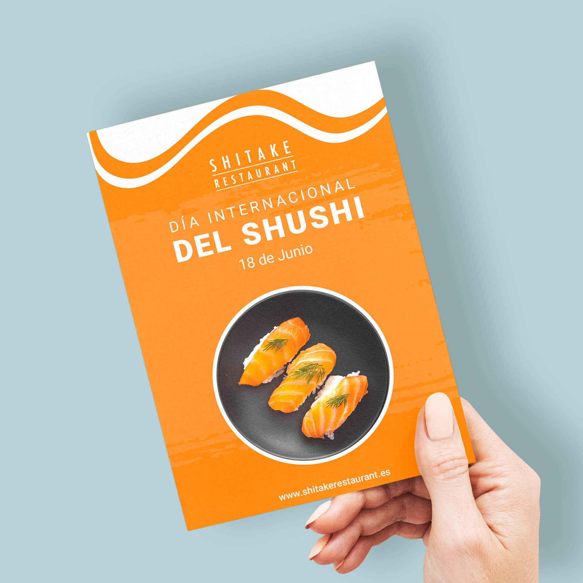 Imagen de un flyer en tamaño aA5, publicitando el día internacional del shushi del restaurante Shitake, sostenido por una mano de mujer.