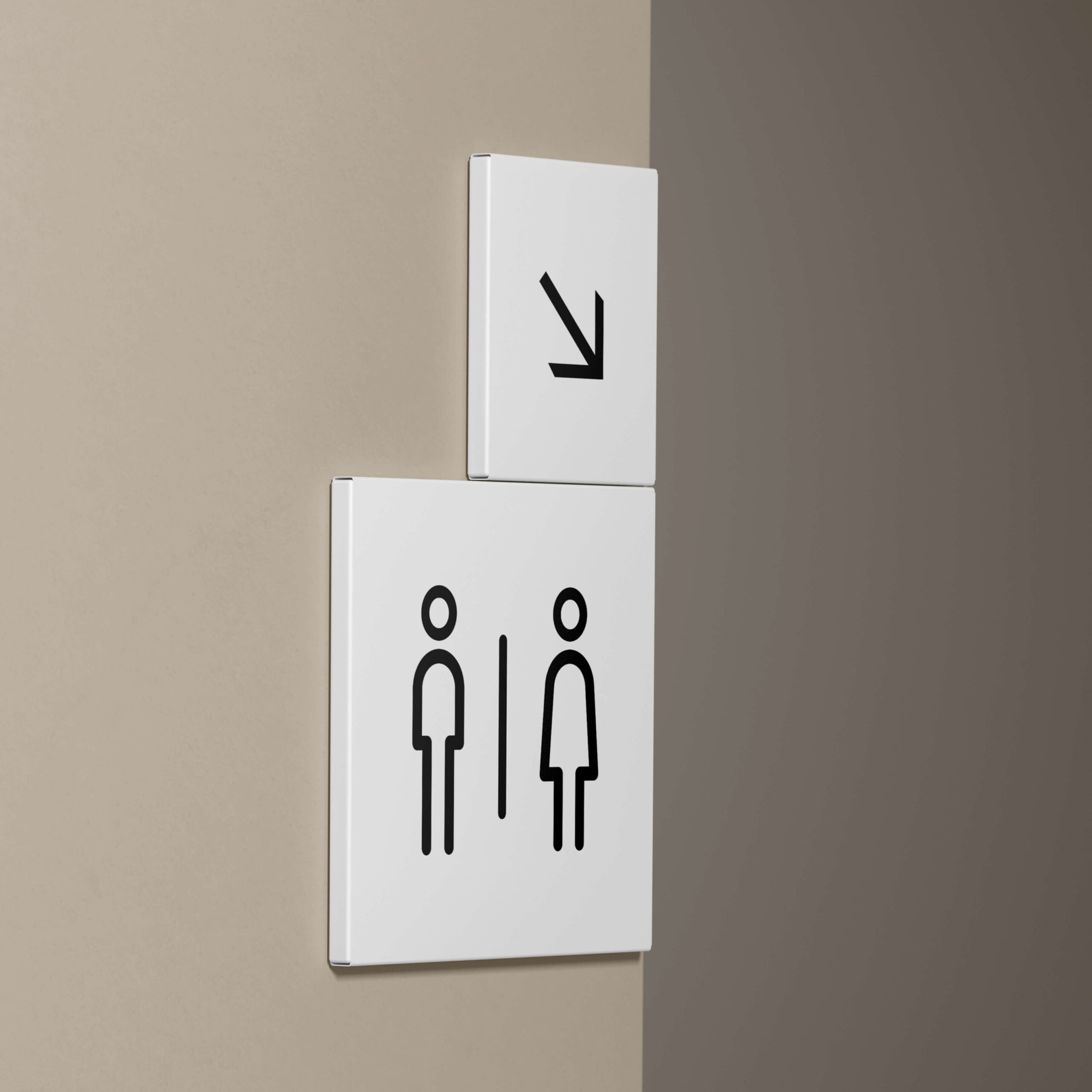 Imagen de dos pvc blancos cuadrados, colocados en una esquina de la pared, con el icono de una flecha y de los WC del edificio.