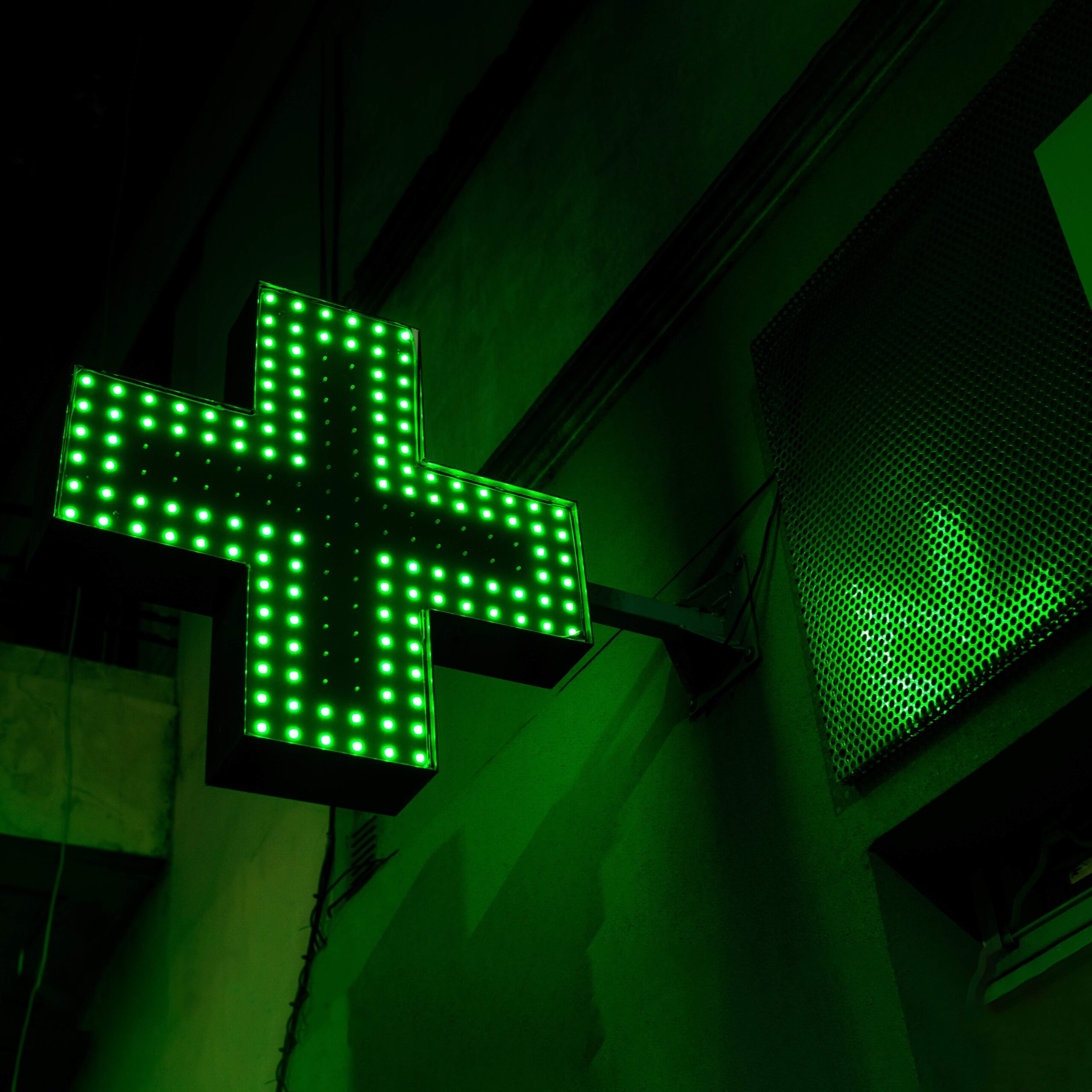 Imagen de noche de la banderola de una farmacia iluminada con leds verdes