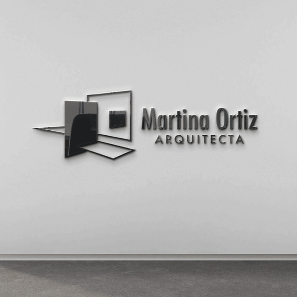 Imagen de unas letras corpóreas de metal con el Logotipo de la arquitecta Martina Ortiz, colocadas en la pared blanca de su oficina.